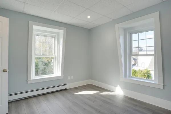 an empty room with wooden floor and windows