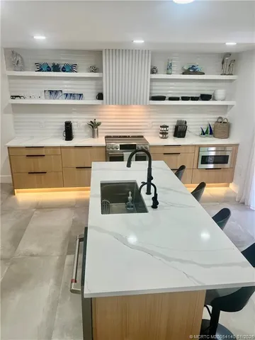 a kitchen with a sink a stove and chairs