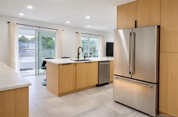 a kitchen with stainless steel appliances a refrigerator a sink a stove a washer dryer and white cabinets
