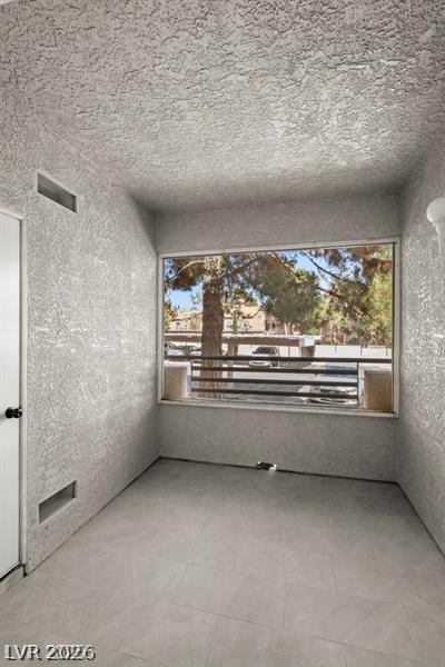 3320 South Fort Apache Road, Unit 125 Las Vegas, NV 89117 - Photo 22 of 26 A well-lit interior space with textured walls and durable tile flooring, perfect for a cozy retreat.