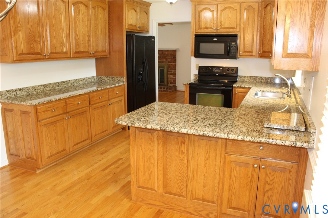 16524 Benmore Road Moseley, VA 23120 - Photo 19 of 43 a kitchen with stainless steel appliances granite countertop a refrigerator a stove top oven and granite countertops with wooden floor