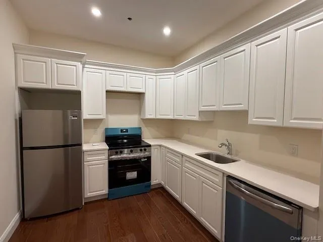 a kitchen with a sink a refrigerator and white cabinets
