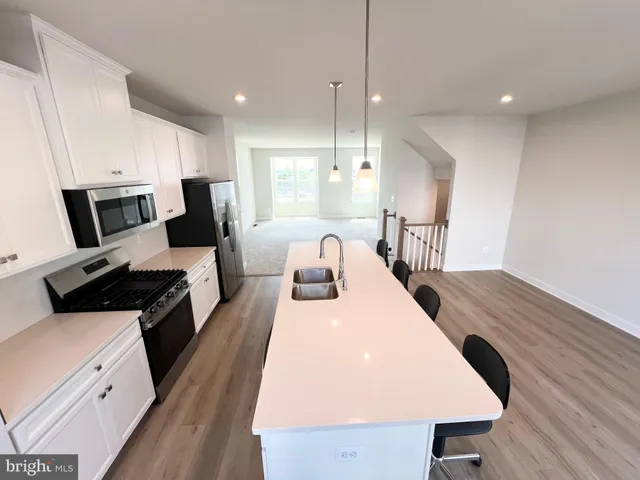 a large kitchen with kitchen island a stove a sink a refrigerator and cabinets