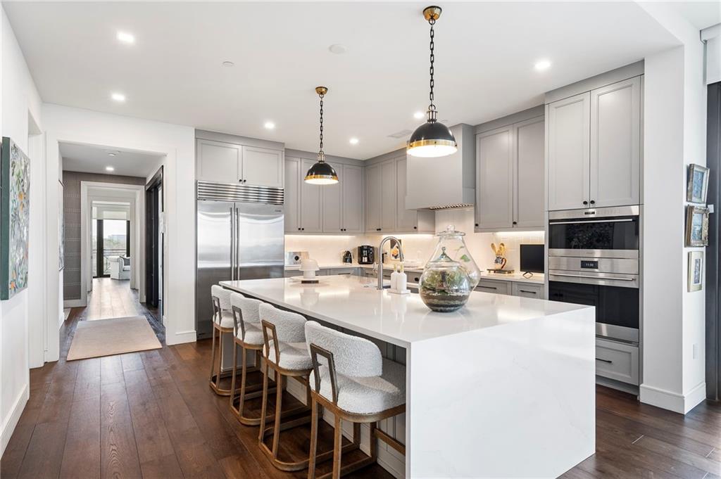 2520 Peachtree Road West, Unit 1203 Atlanta, GA 30305 - Photo 14 of 65 a kitchen with stainless steel appliances kitchen island granite countertop a stove a sink a refrigerator and chairs with wooden floor