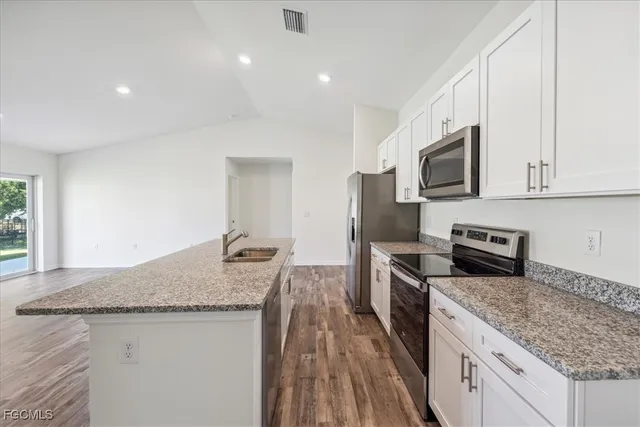 a kitchen with stainless steel appliances granite countertop a sink stove microwave and refrigerator