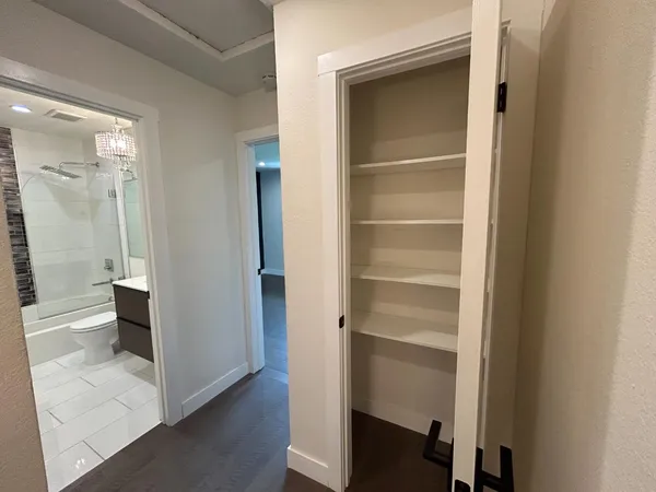 a view of a hallway with wooden floor and a bathroom