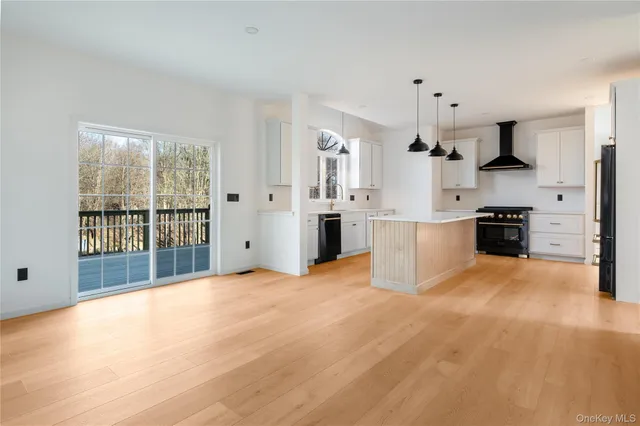 a large white kitchen with stainless steel appliances granite countertop a stove and a sink with cabinets