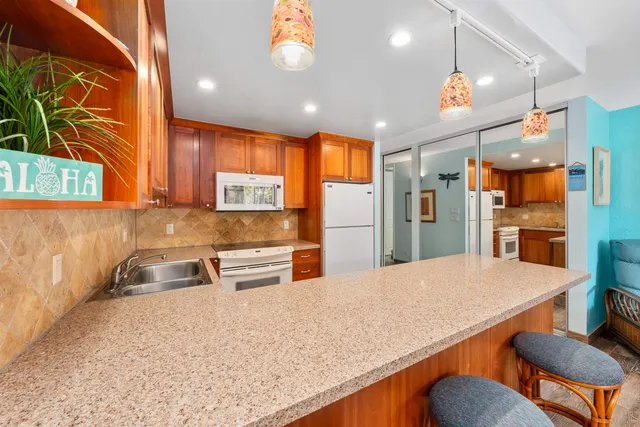 a kitchen with stainless steel appliances kitchen island granite countertop wooden cabinets and a refrigerator