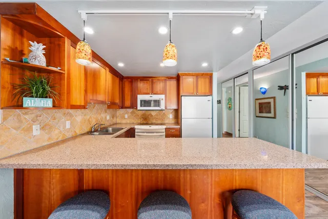 a kitchen with stainless steel appliances granite countertop a sink a stove a refrigerator cabinets and chairs