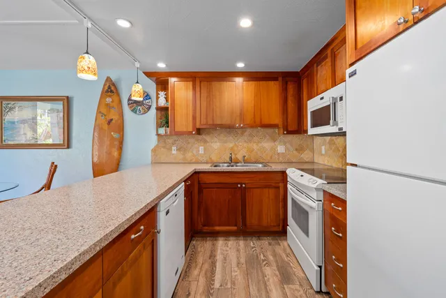 a kitchen with stainless steel appliances granite countertop a sink a stove and a wooden cabinets
