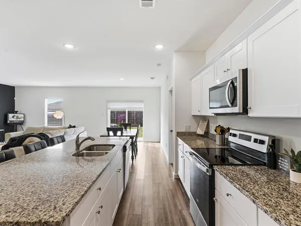a large kitchen with stainless steel appliances granite countertop a lot of counter space and wooden floor