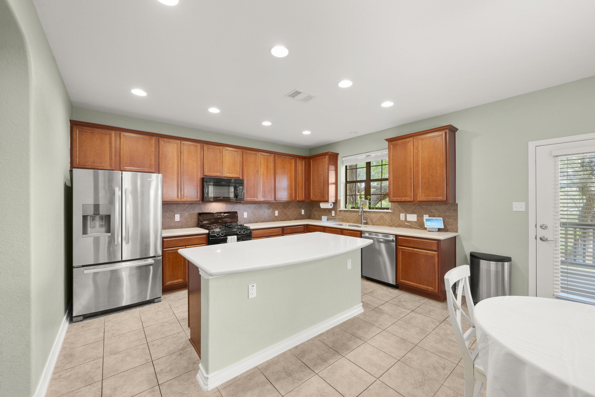 7629 Brecourt Manor Way Austin, TX 78739 - Photo 4 of 40 a kitchen with stainless steel appliances granite countertop a refrigerator a sink dishwasher a stove top oven a dining table and chairs with wooden floor