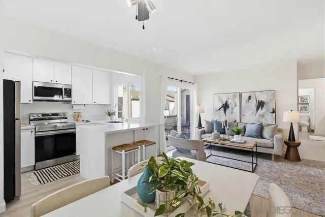 a living room with stainless steel appliances furniture and a view of kitchen