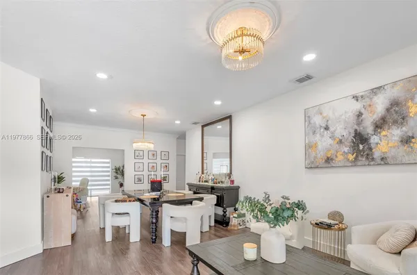 a room with lots of white furniture and wooden floor