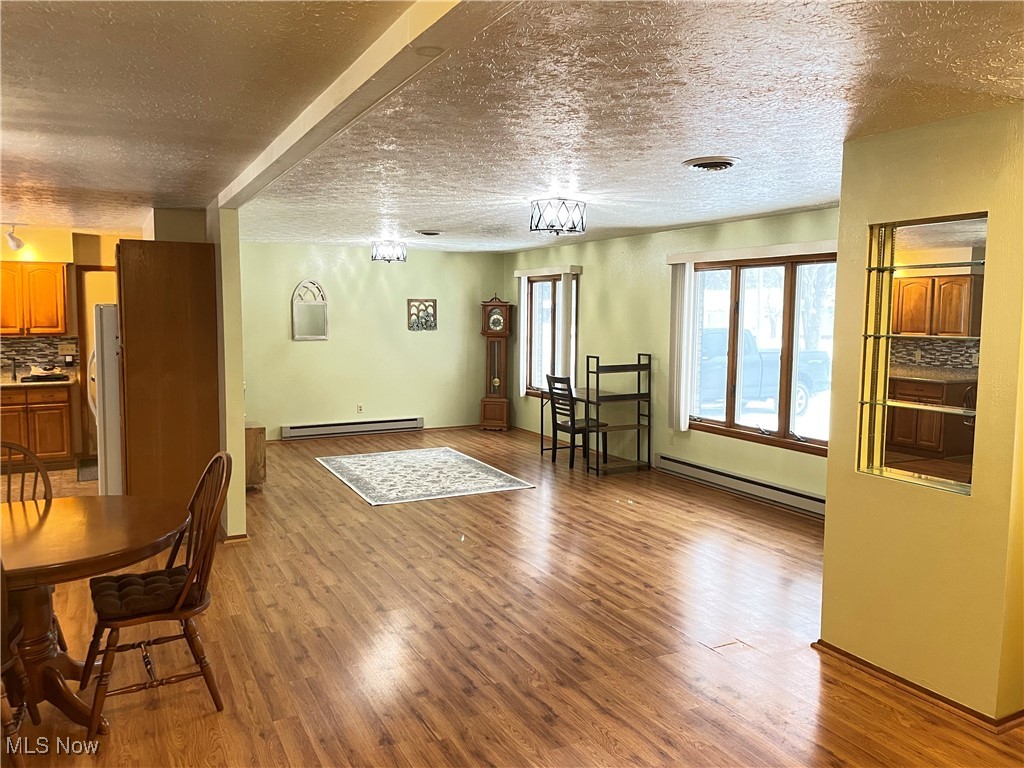 1381 Robb Road Conneaut, OH 44030 - Photo 10 of 50 Living area featuring light wood-style flooring, baseboard heating, and a textured ceiling