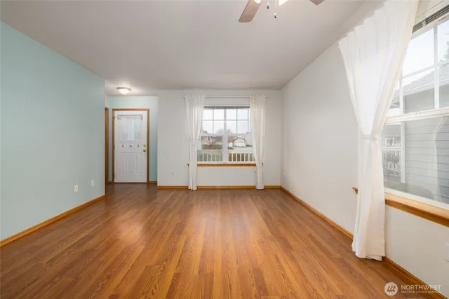 an empty room with wooden floor kitchen view and a window