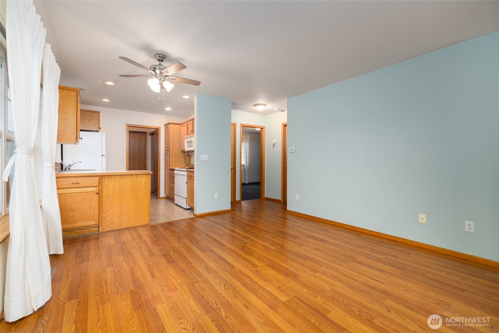 1154 Sinclair Way Burlington, WA 98233 - Photo 7 of 22 a view of an empty room with wooden floor and a kitchen