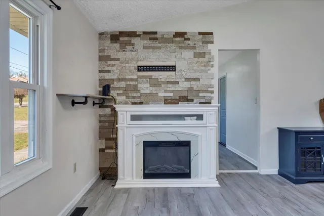 an empty room with wooden floor chandelier and windows