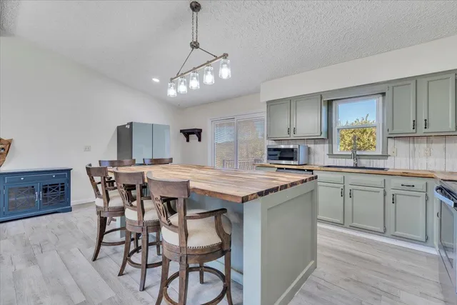 a kitchen with stainless steel appliances granite countertop a kitchen island hardwood floor sink stove dining table and chairs