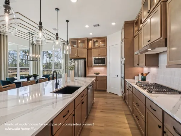 a kitchen with stainless steel appliances granite countertop a sink a stove and a wooden floors