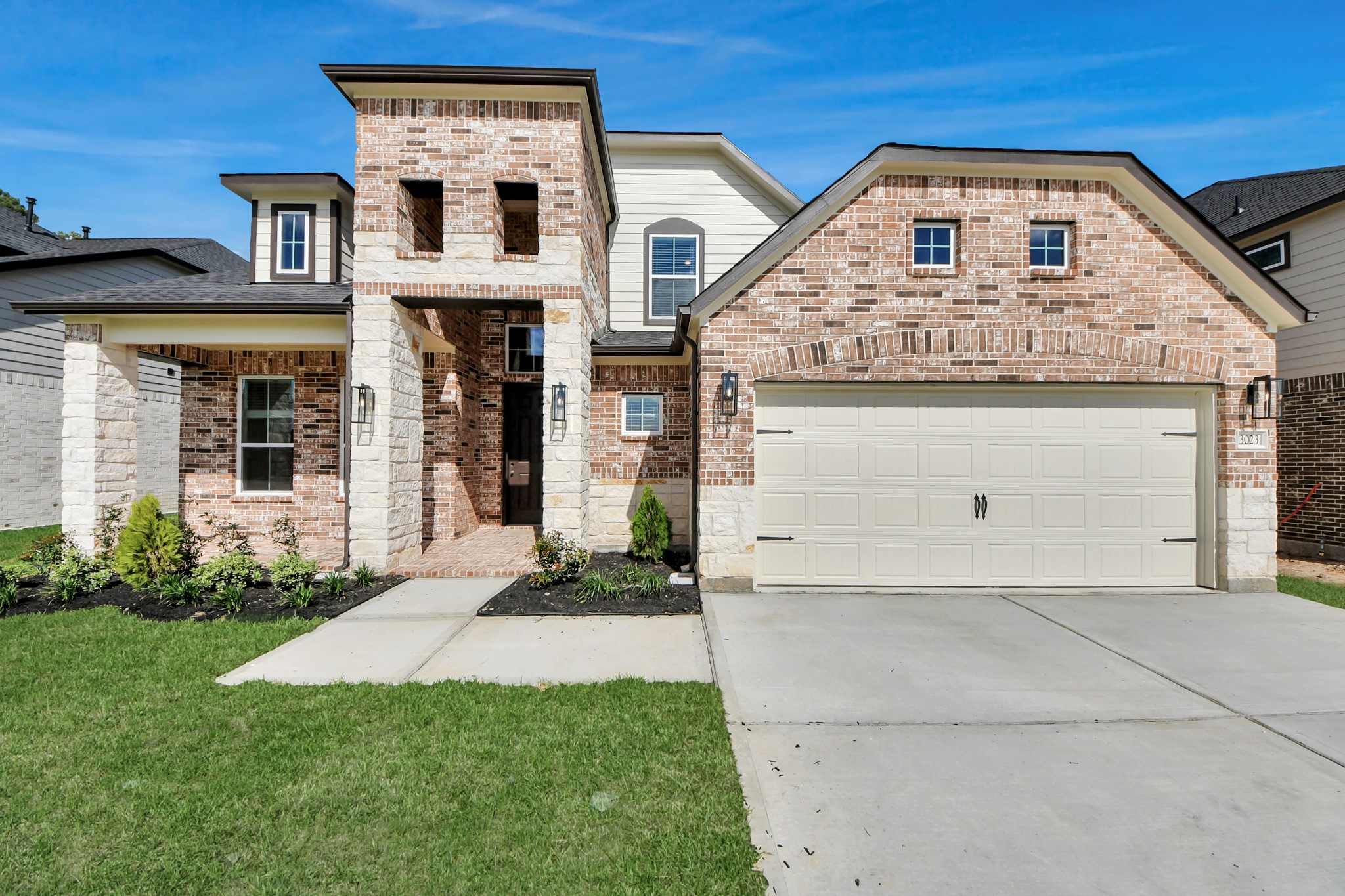 3023 Native Spg Drive Spring, TX 77373 - Photo 3 of 50 Meticulously maintained yard and lush landscape, paired with a premium elevation featuring captivating brick accents. Modern coach lights add a touch of contemporary elegance to the exterior.