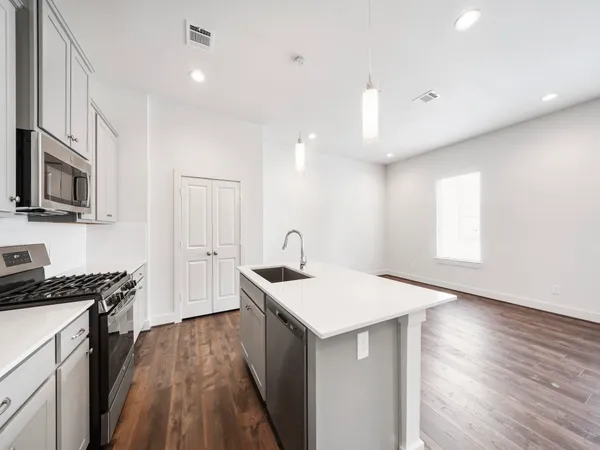a kitchen with a refrigerator a sink and dishwasher with wooden floor