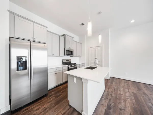 a kitchen with kitchen island a sink a stove a refrigerator and white cabinets