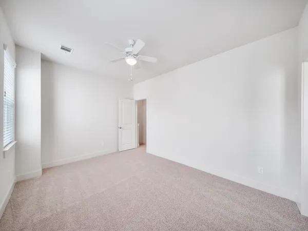an empty room with chandelier fan and windows