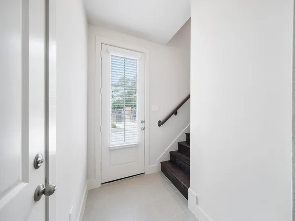 an empty room with a chandelier fan and windows