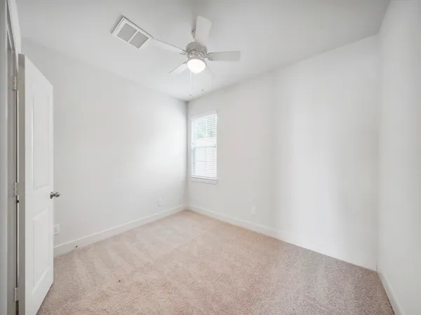 an empty room with a ceiling fan and closet area