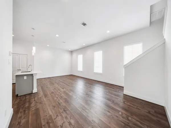 a view of a kitchen with kitchen island a sink wooden floor and a refrigerator