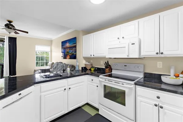 a kitchen with granite countertop white cabinets and white appliances