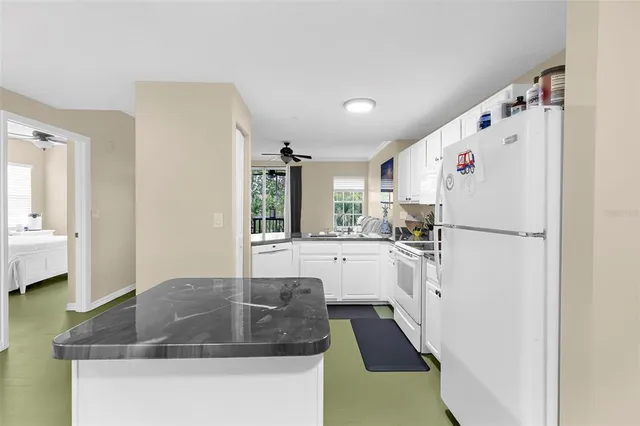 a kitchen with refrigerator a sink and white cabinets