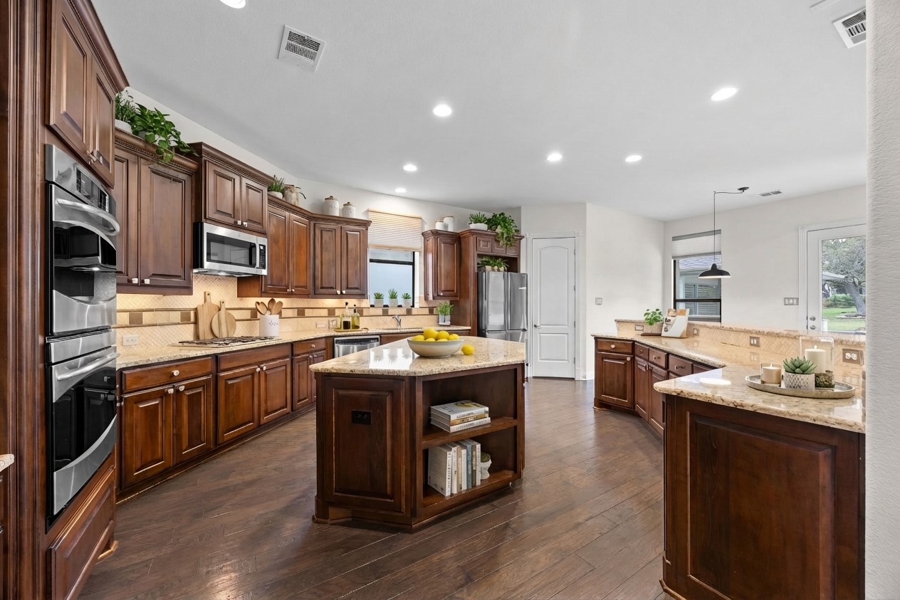2300 Lakehurst Road Spicewood, TX 78669 - Photo 12 of 40 Kitchen with a center island, open shelves, decorative light fixtures, dark wood-style floors, and light stone countertops- virtually staged