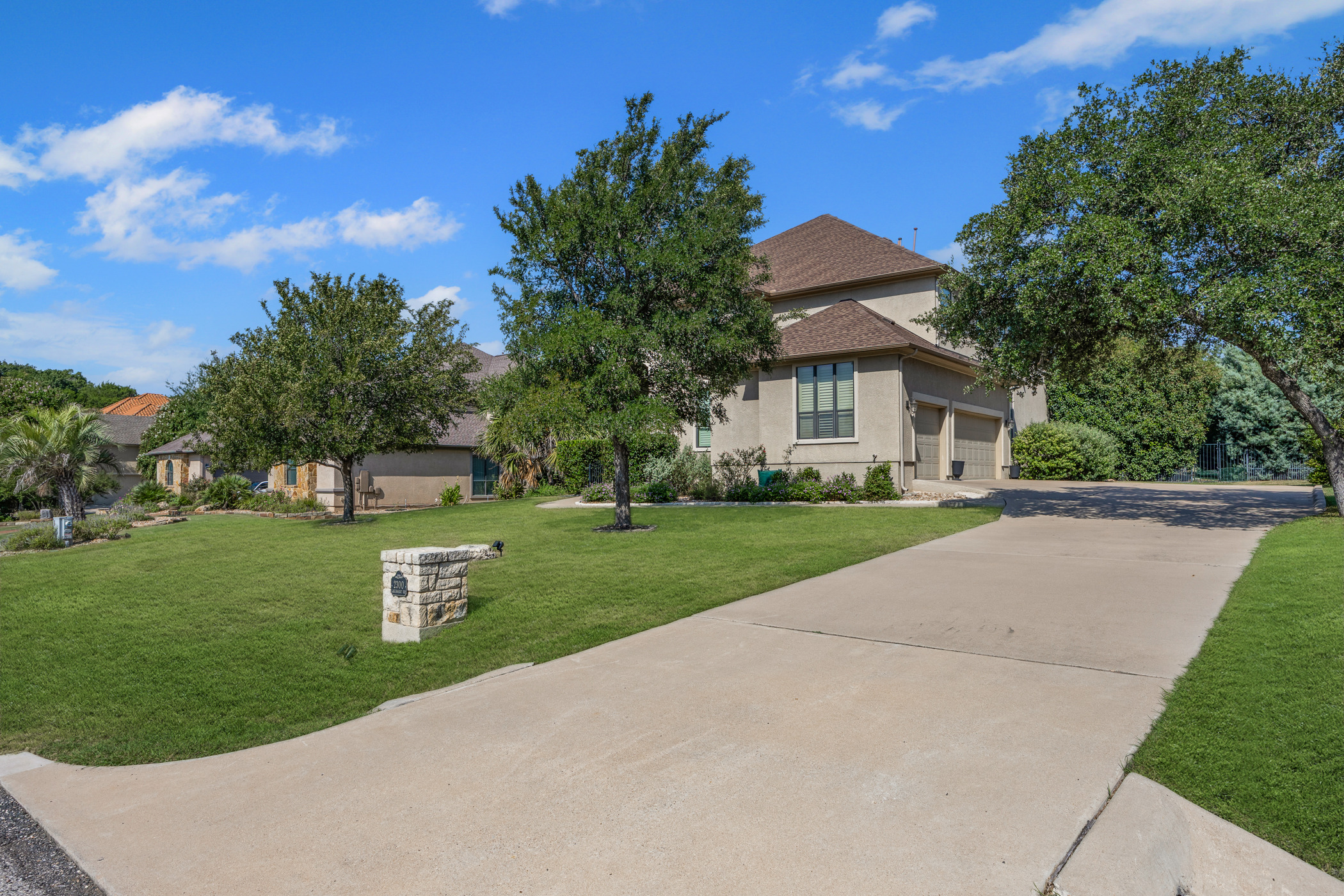 2300 Lakehurst Road Spicewood, TX 78669 - Photo 30 of 40 View of front facade featuring a front yard, concrete driveway, stucco siding, and an attached garage