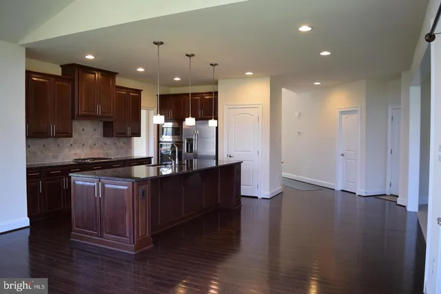 a kitchen with stainless steel appliances kitchen island granite countertop a large counter top and wooden floors