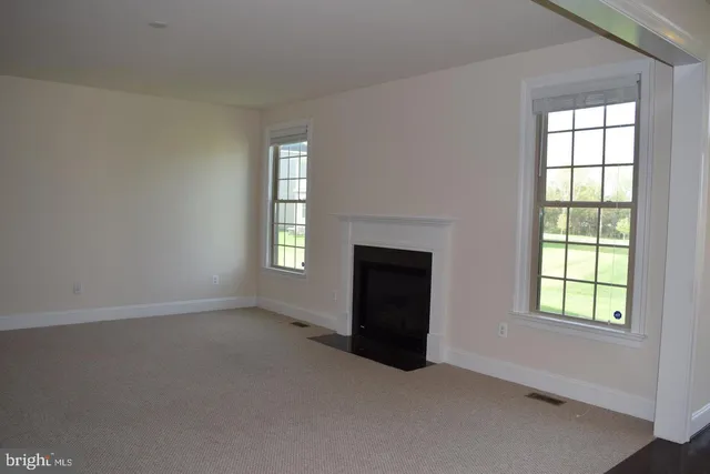 an empty room with windows and fireplace
