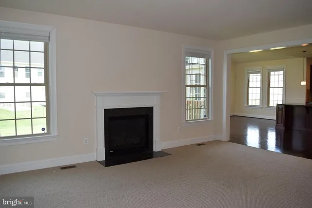 an empty room with windows and fireplace