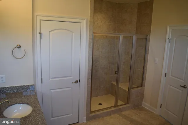 a bathroom with a granite countertop sink a mirror and shower