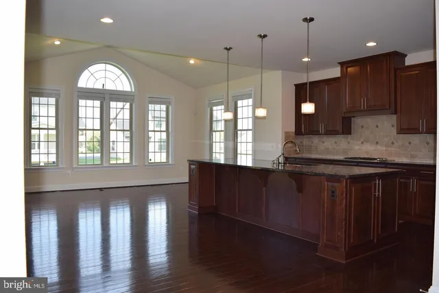 a open kitchen with granite countertop a stove a sink a window and wooden floor