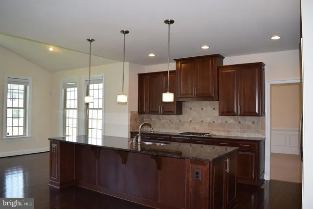 a kitchen with kitchen island granite countertop a sink a counter space appliances and a window
