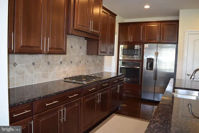 a kitchen with granite countertop a refrigerator stove and cabinets