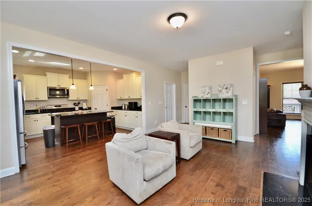 a living room with furniture wooden floor and kitchen view