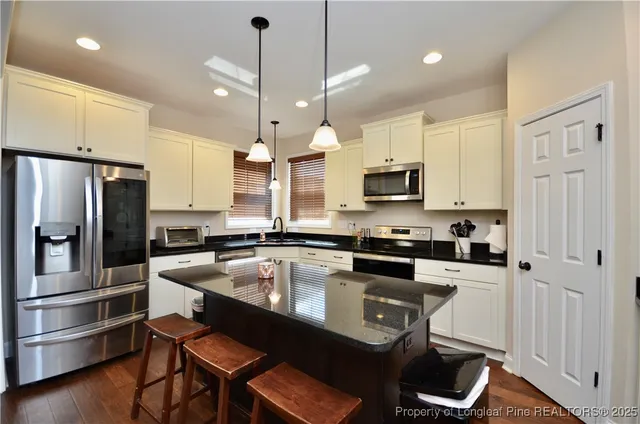 a kitchen with a refrigerator a stove a sink and white cabinets with wooden floor