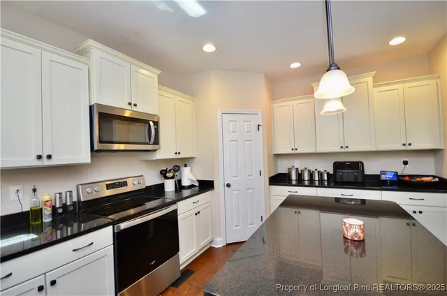 a kitchen with granite countertop a stove a sink a refrigerator and cabinets