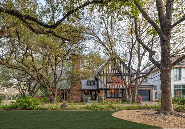 a front view of a house with a garden and tree