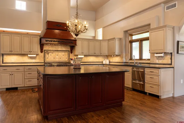 a kitchen with stainless steel appliances granite countertop a sink a stove and a wooden floors