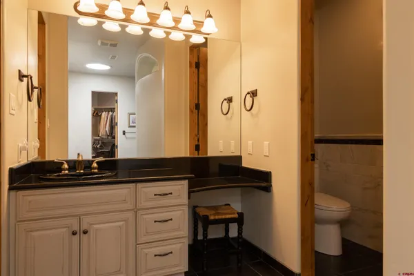 a bathroom with a granite countertop sink a toilet a mirror and shower