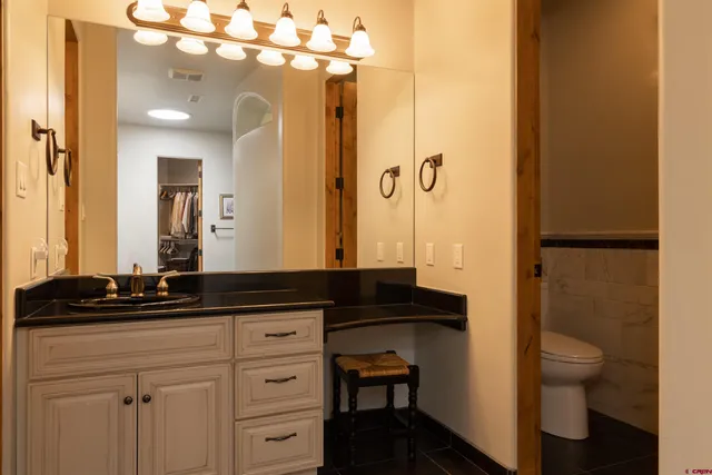 a bathroom with a granite countertop sink a toilet a mirror and shower