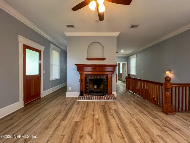 a view of a livingroom with a fireplace wooden floor and chandelier fan
